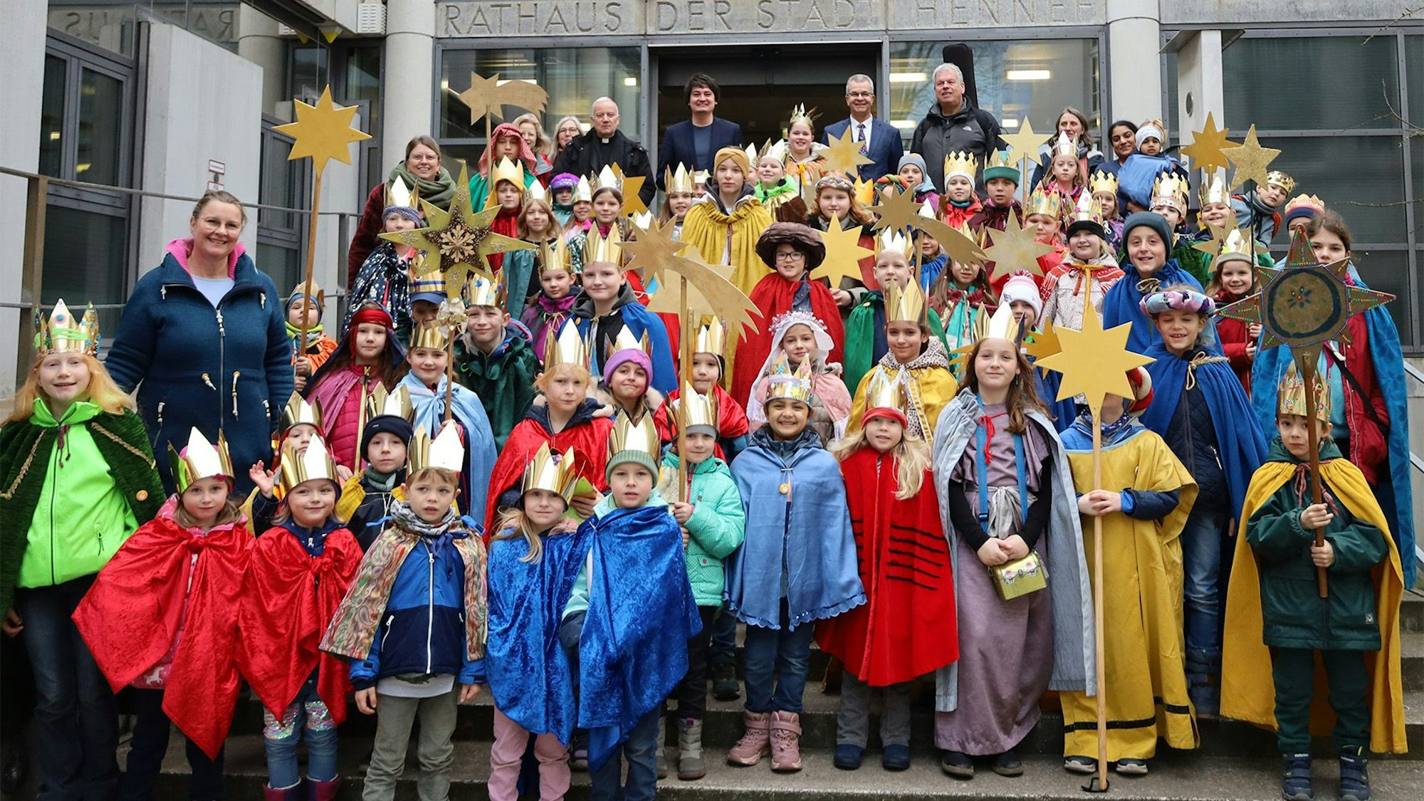 Rund 60 als Heilige Drei Könige verkleidete Kinder stehen auf der Hennefer Rathaustreppe.