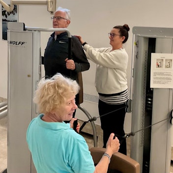 In einem Fitnessstudio trainieren ein Senior und eine ältere Dame.