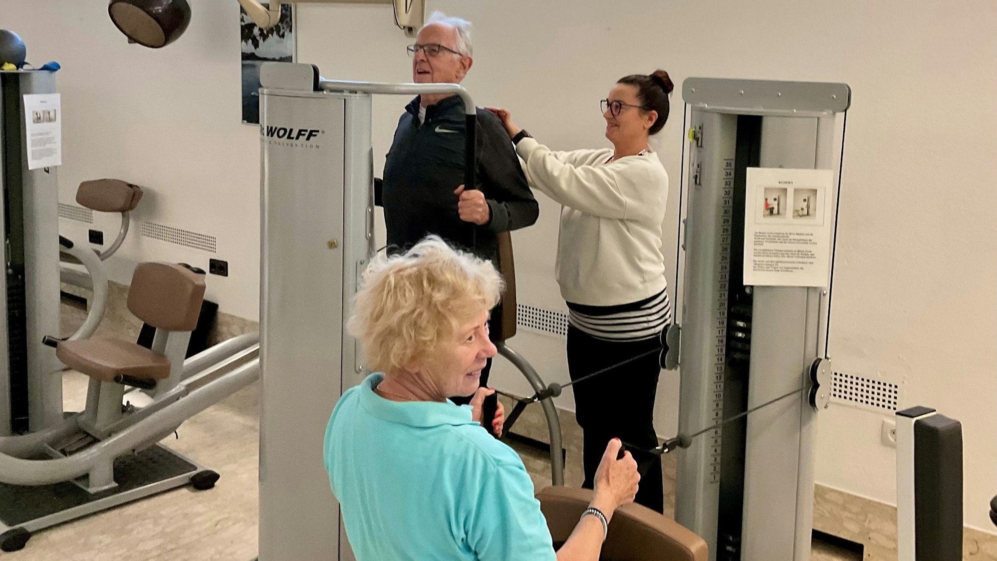 In einem Fitnessstudio trainieren ein Senior und eine ältere Dame.