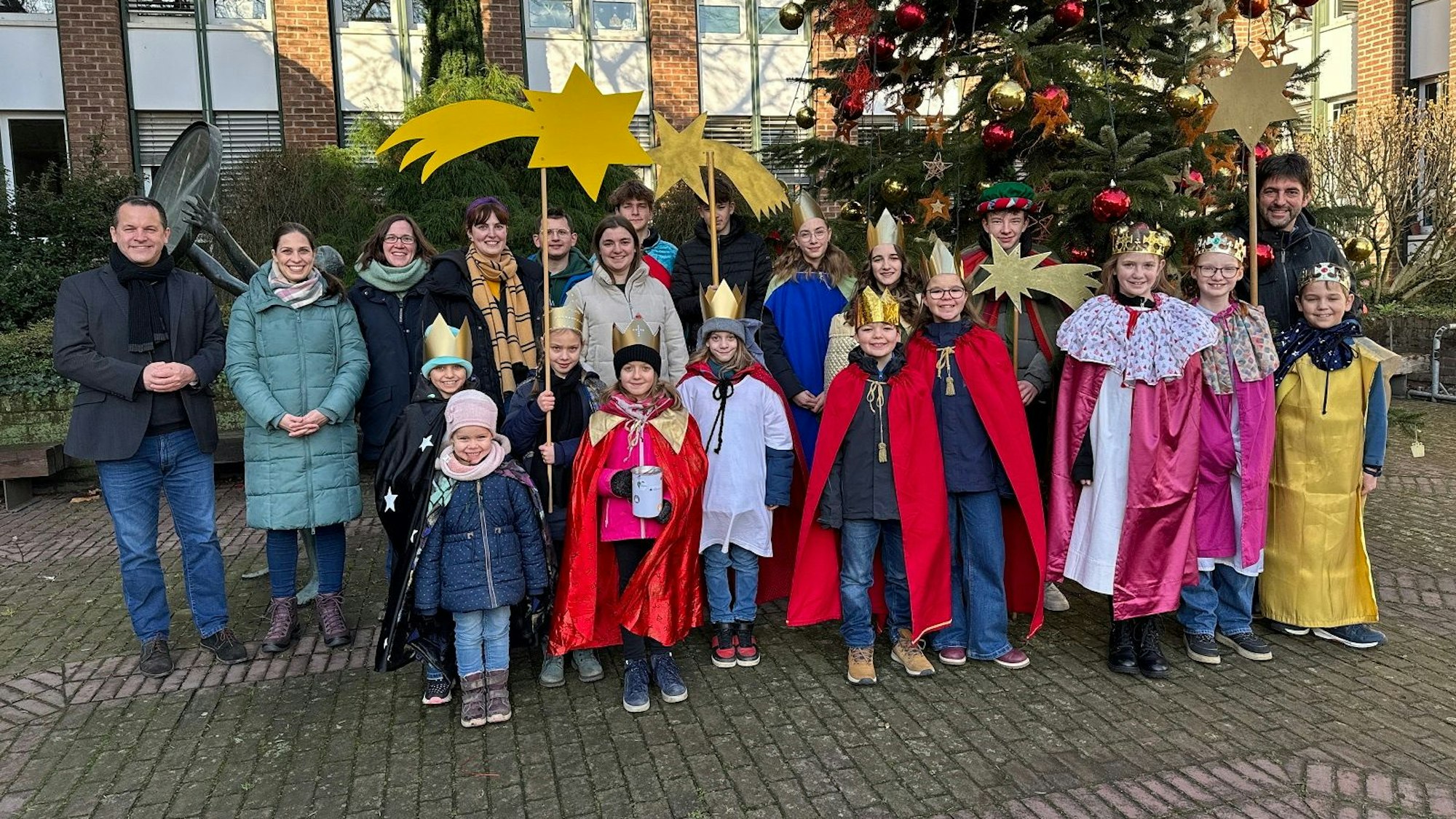 Kinder und Erwachsene lächeln in die Kamera.