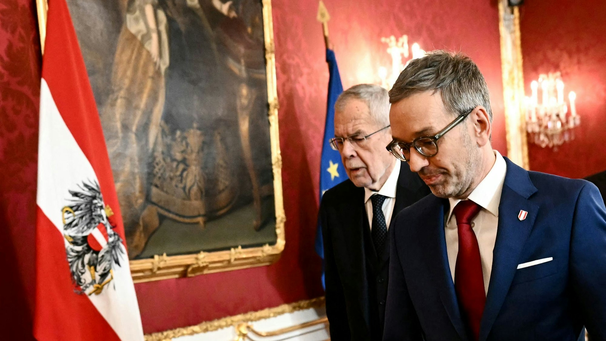 Alexander Van der Bellen und Herbert Kickl gehen eine Wand mit Österreich-Flagge entlang.
