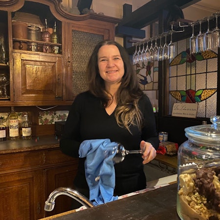 Zu sehen ist Renate Schmolz, die hinter der Theke des Lokals steht.