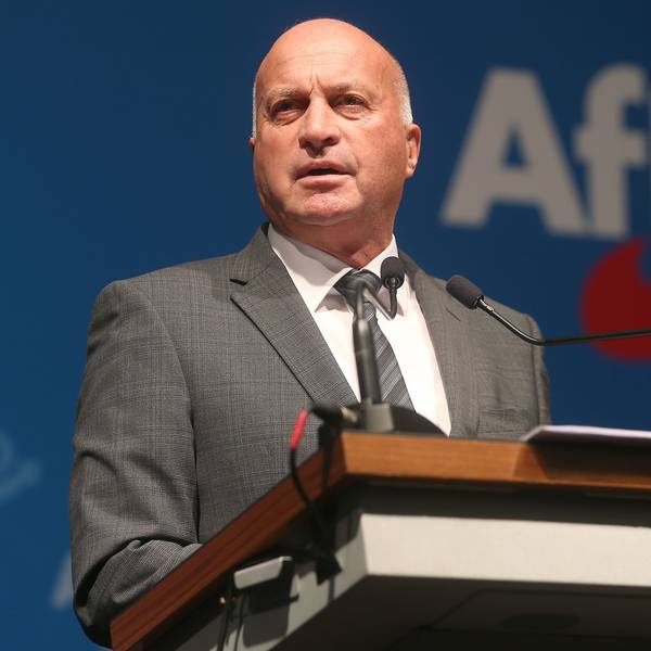 Rüdiger Lucassen steht an einem Rednerpult, auf einer Wand dahinter steht das AfD-Logo.