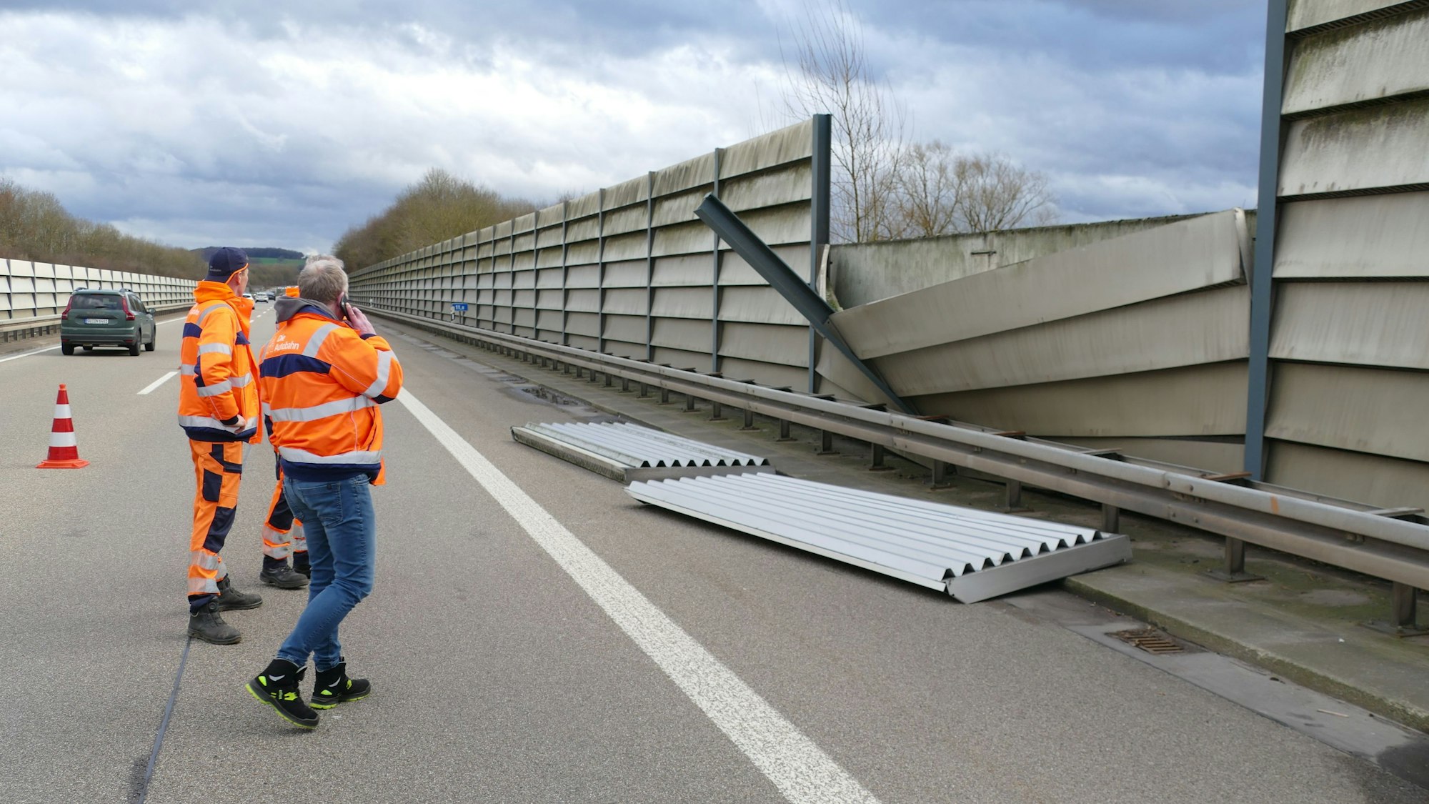 Arbeiter stehen vor den Teilen einer Lärmschutzwand auf der Autobahn 560 in Hennef. Durch den Sturm ist ein Stahlträger aus der Verankerung gerissen.