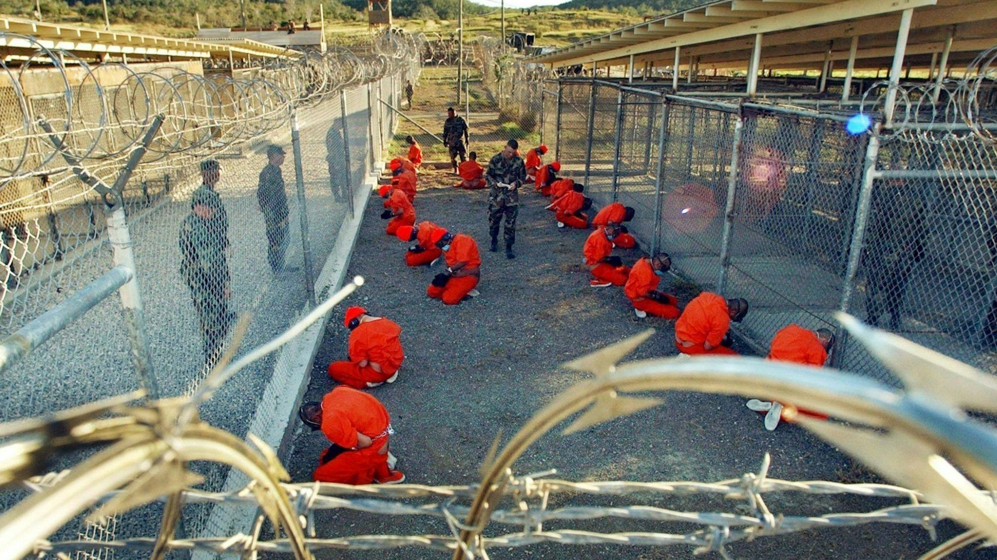 Ein von der US-Armee herausgegebenes Foto zeigt in orangefarbene Overalls gekleidete Häftlinge, die im Camp X-Ray auf dem US-Marinestützpunkt Guantanamo Bay auf Kuba auf dem Boden knien.