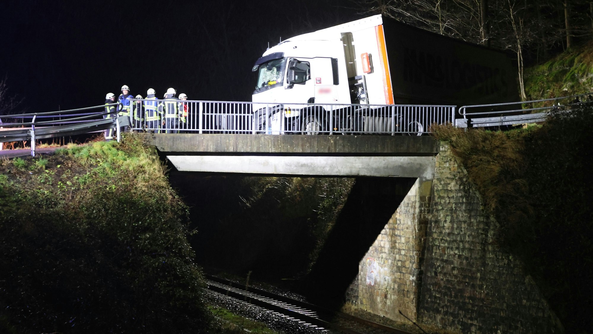 Eine Einsatzkraft der Feuerwehr steht neben einem Einsatzfahrzeug der Feuerwehr.