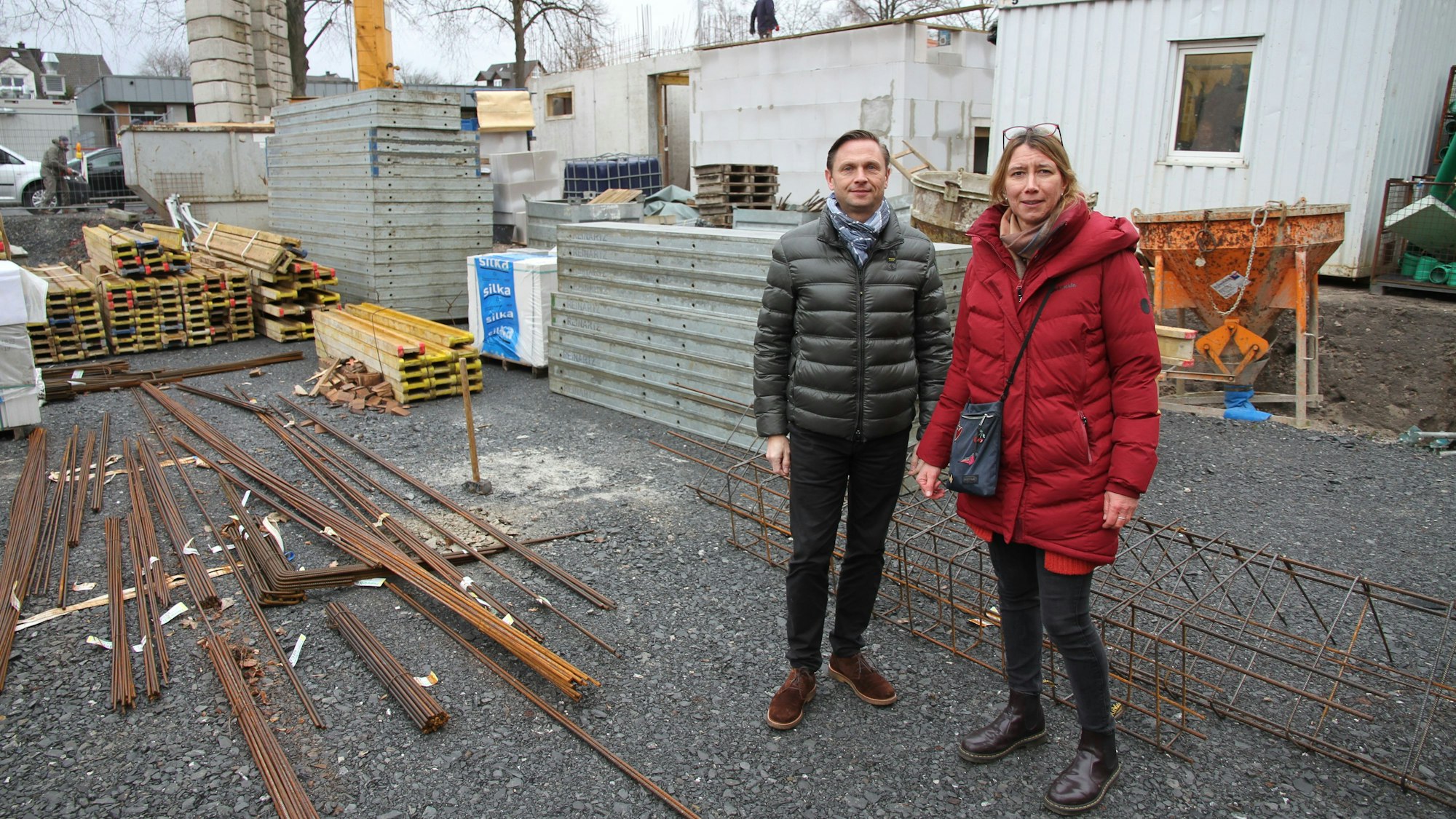 Ein Mann und eine Frau in Winterjacken auf einer Baustelle