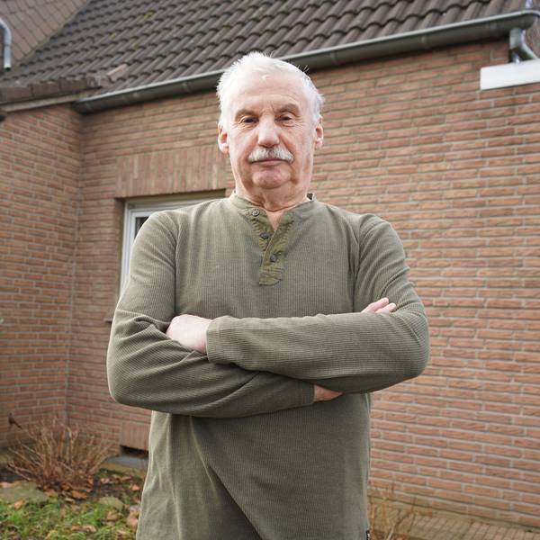 Das Foto zeigt einen Mann mit verschränkten Armen vor einem Haus.