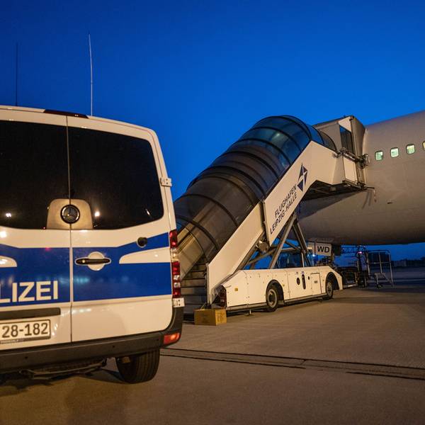 Ein Polizeiwagen steht vor einem Abschiebeflugzeug am Flughafen.