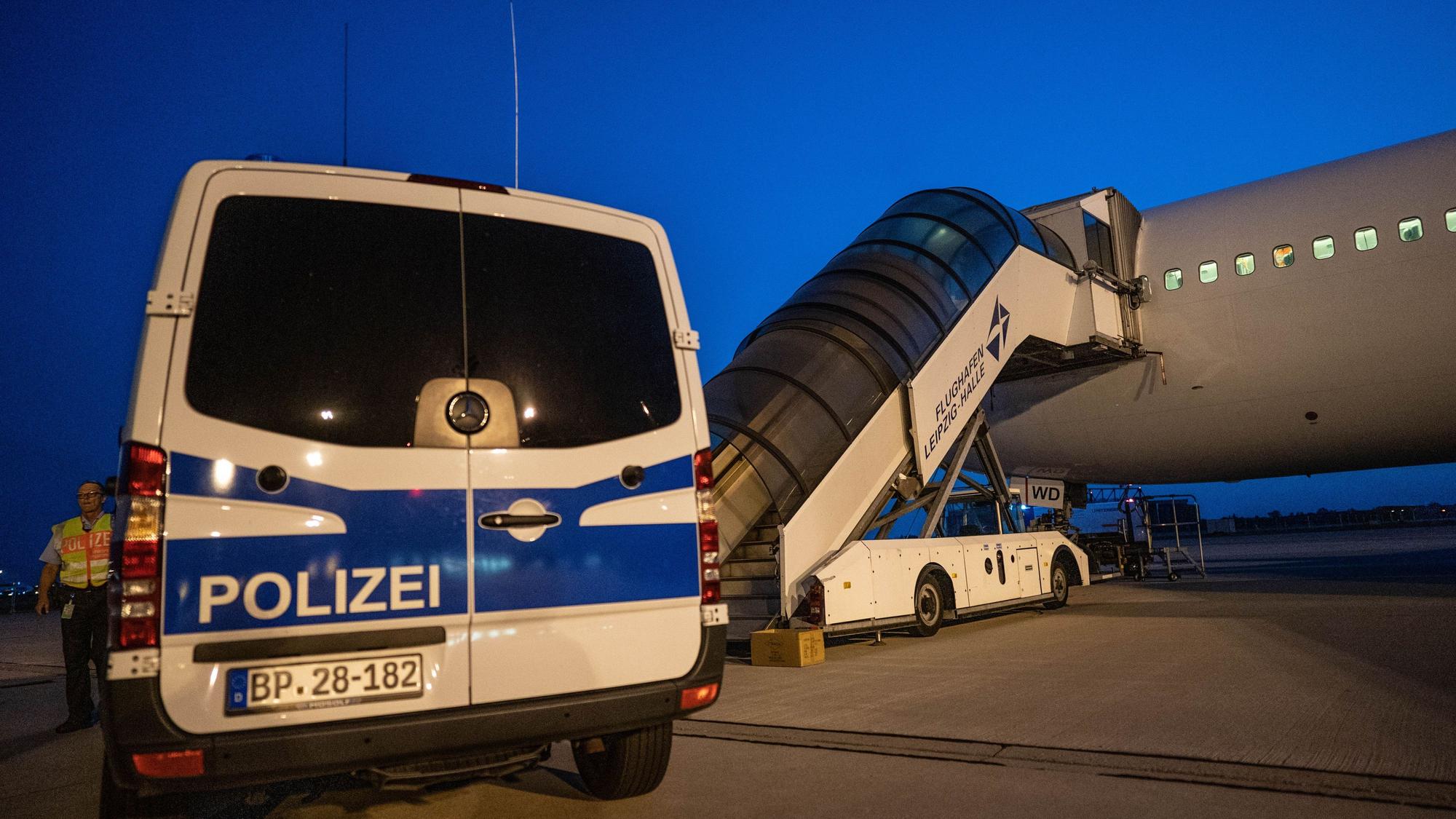 Ein Polizeiwagen steht vor einem Abschiebeflugzeug am Flughafen.