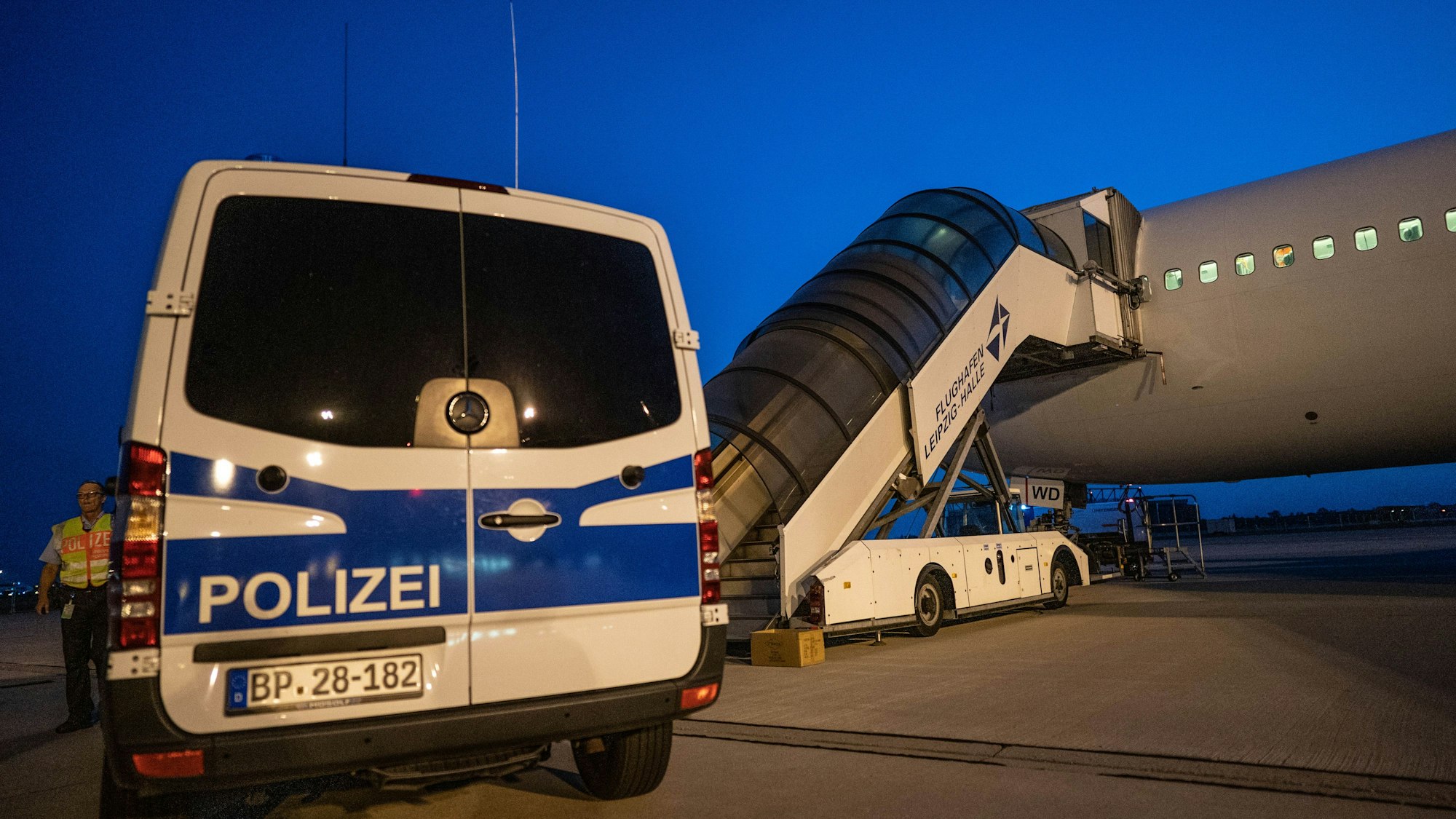 Ein Polizeiwagen steht vor einem Abschiebeflugzeug am Flughafen.