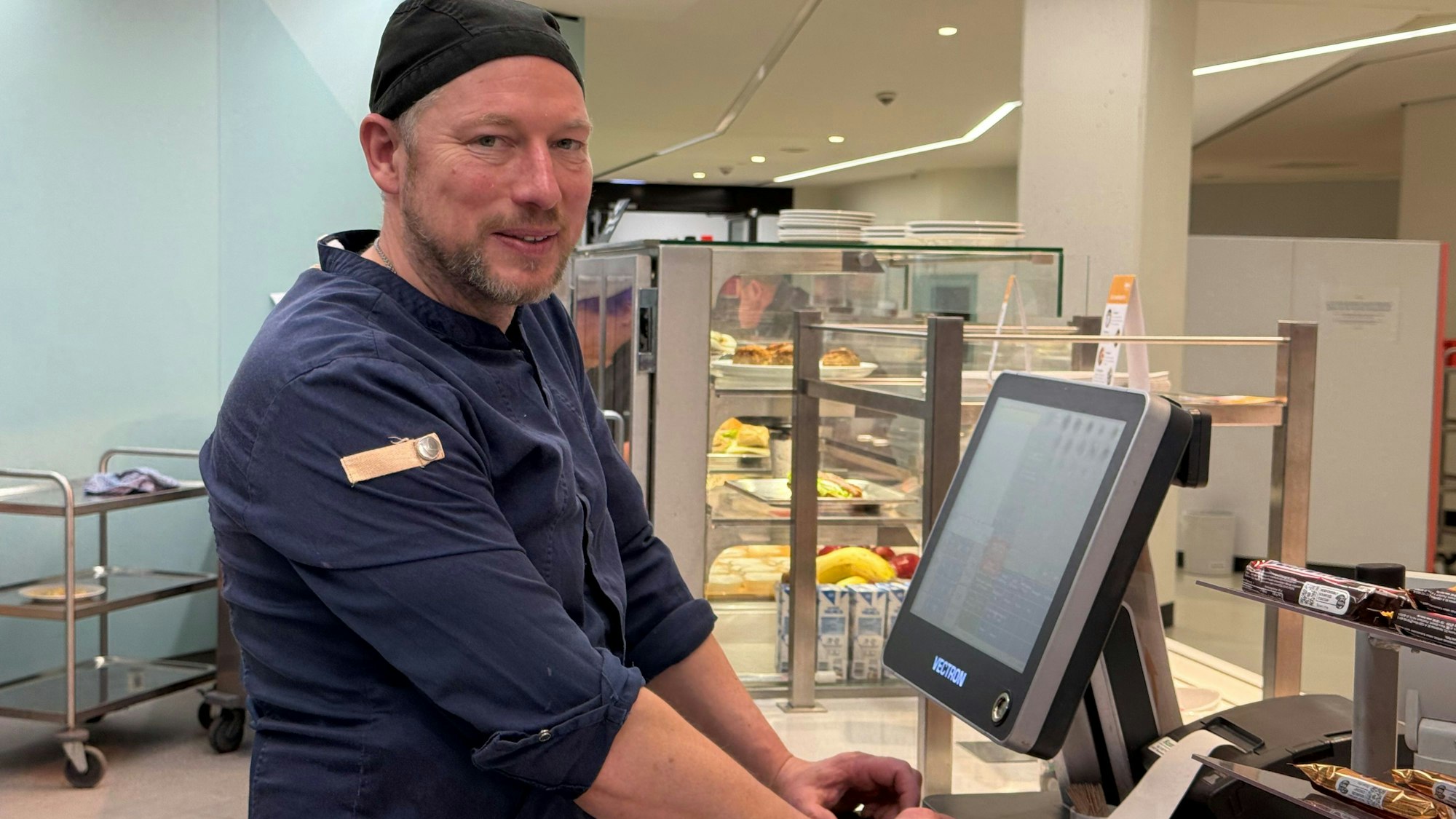 Ein Mann steht in einer Kantine an der Kasse