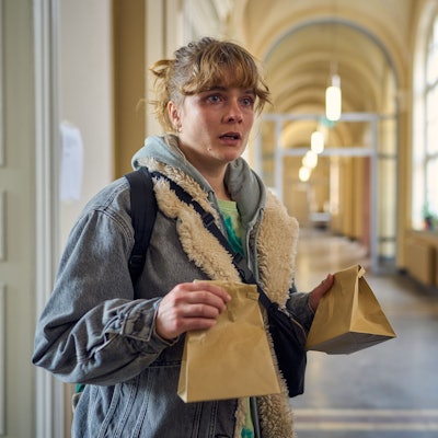 BFF - Best Family Forever : Lena (Anna Schimrigk) steht mit zwei Kotztüten auf dem Flur der Uni Bonn und schaut entgeistert.