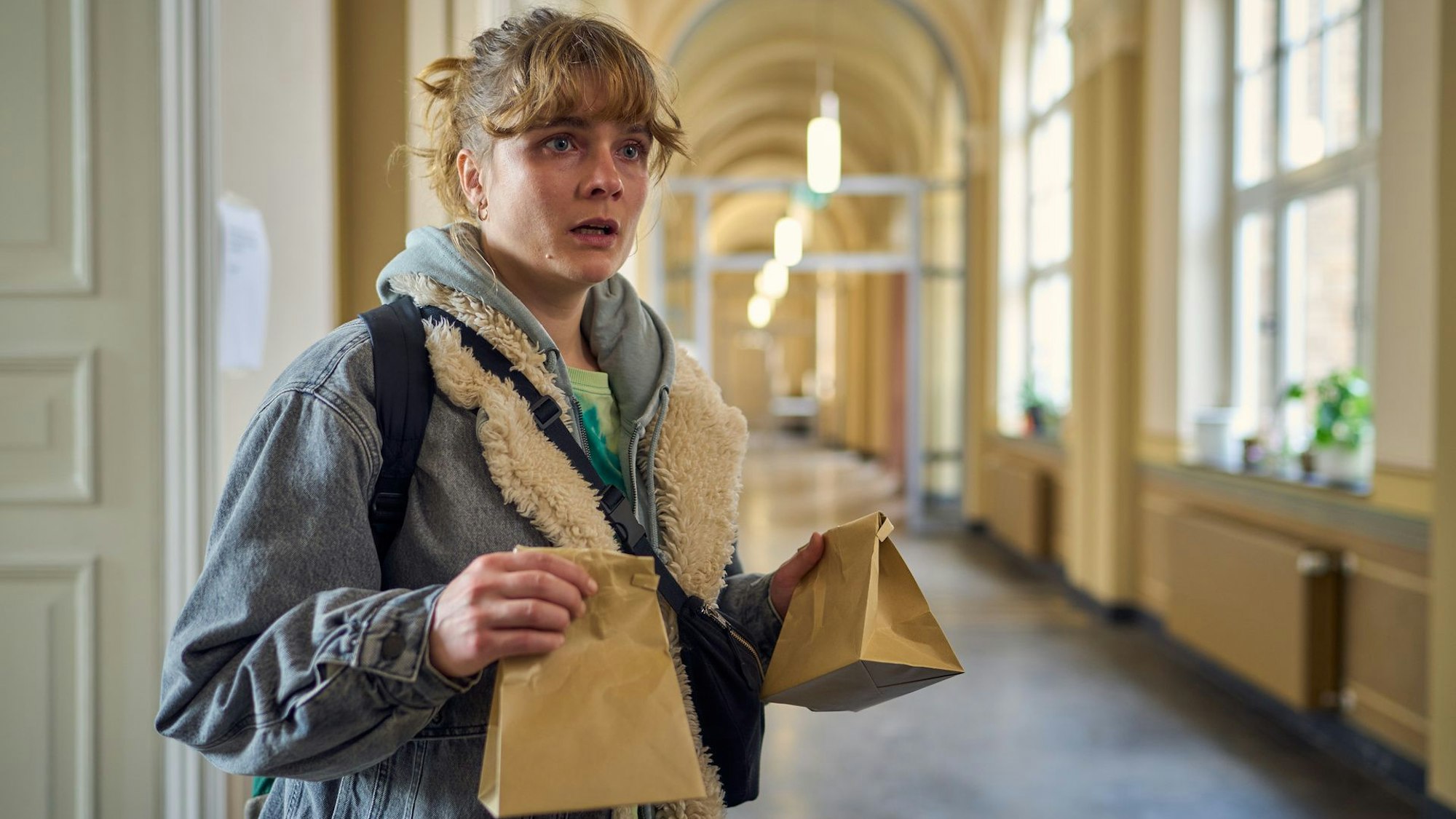 BFF - Best Family Forever : Lena (Anna Schimrigk) steht mit zwei Kotztüten auf dem Flur der Uni Bonn und schaut entgeistert.