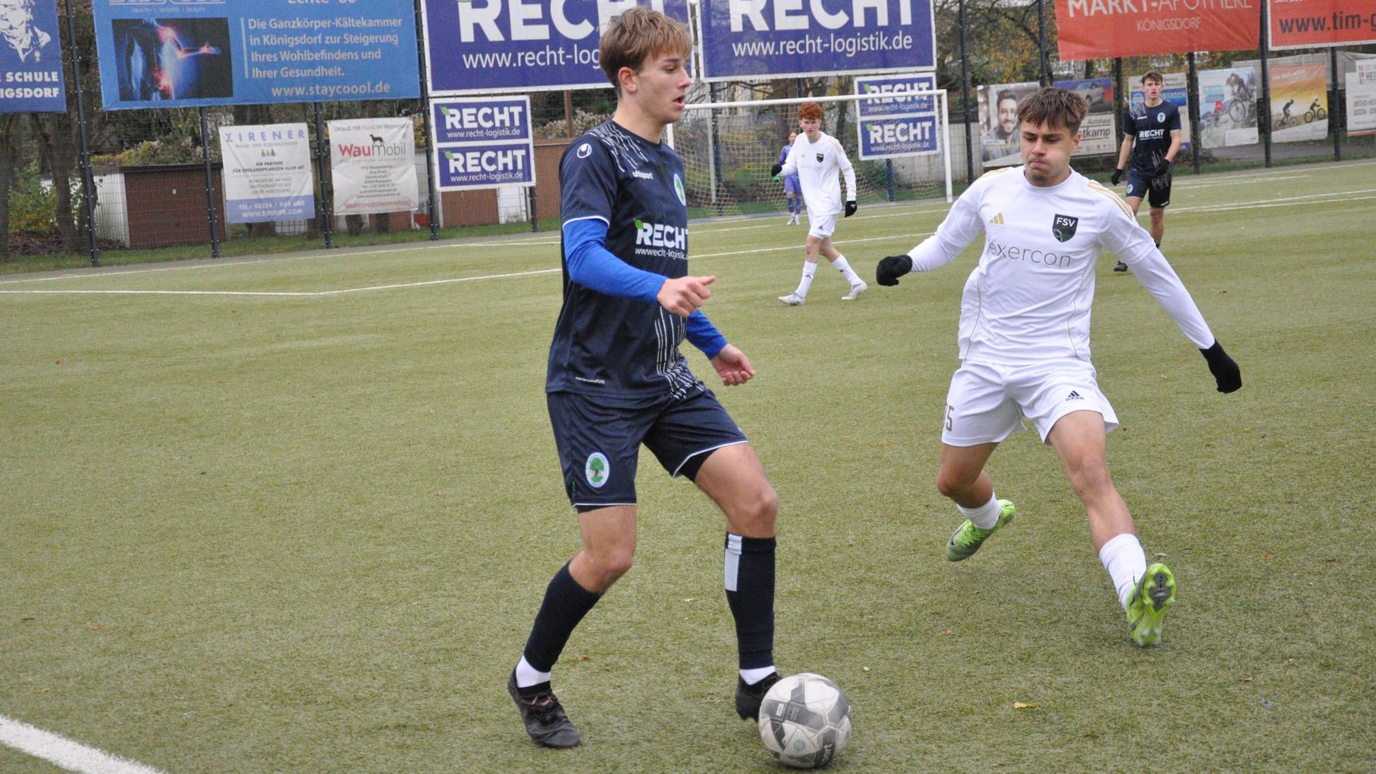 Das Foto zeigt zwei Fußballer im Zweikampf, der blau gekleidete Königsdorfer schirmt den Ball vor dem Gegner ab.