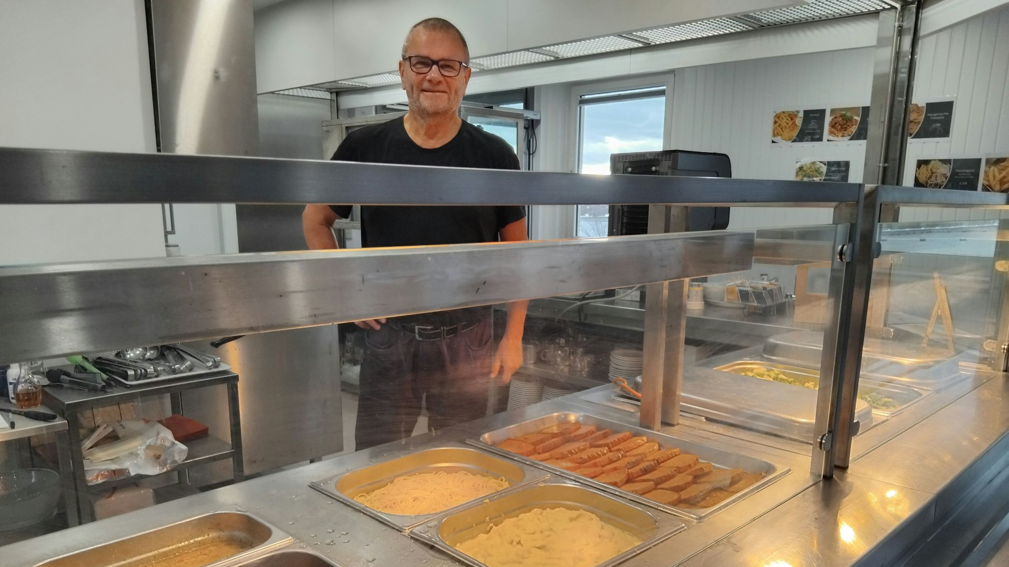 Ein Mann steht hinter einer Essenstheke