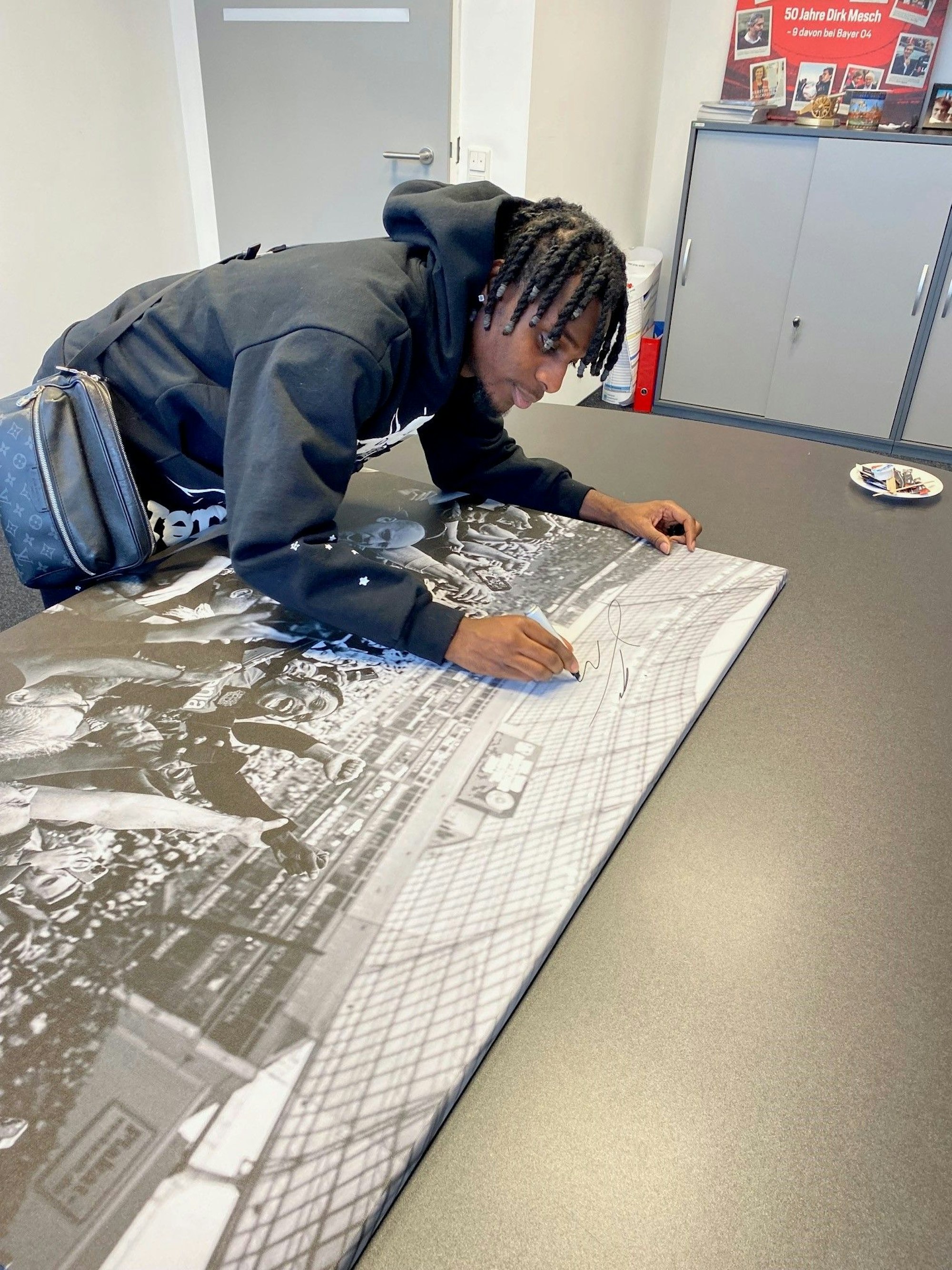 Jeremie Frimpong unterschreibt eine Foto-Leinwand, die wir unter allen KStA-PLUS-Abonennten verlosen.