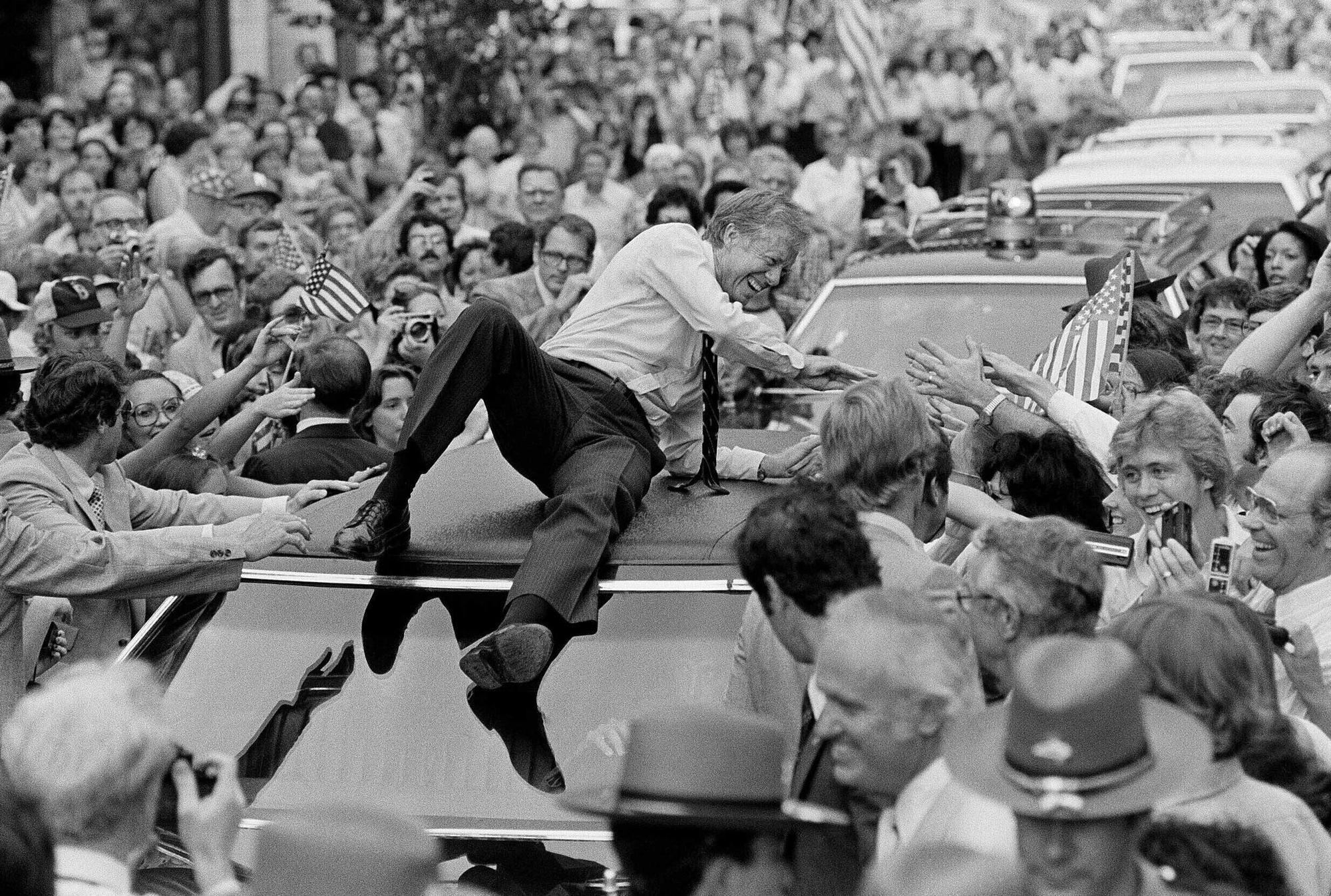 Der damalige US-Präsident Jimmy Carter lehnt sich über das Dach seines Wagens, um auf der Paraderoute durch Bardstown Hände zu schütteln.