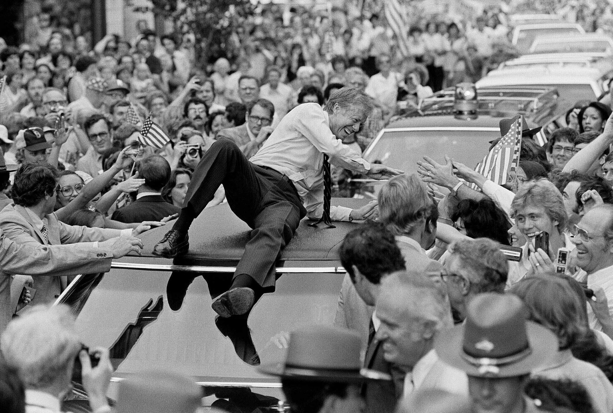 Der damalige US-Präsident Jimmy Carter lehnt sich über das Dach seines Wagens, um auf der Paraderoute durch Bardstown Hände zu schütteln.
