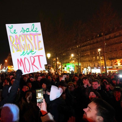 Ein Mann hält in Paris ein Plakat mit der Aufschrift ´Der dreckige Rassist ist tot` in die Höhe, während sich Menschen auf dem Place de la Republique versammeln, um an der Kundgebung ´Le Pen ist tot!» teilzunehmen, die von der Neuen Antikapitalistischen Partei (NPA) im Zentrum von Paris organisiert wurde, wenige Stunden nach dem Tod des französischen rechtsextremen Politikers Jean-Marie Le Pen.