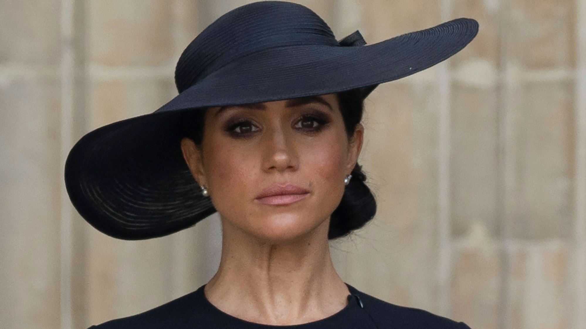 Herzogin Meghan schaut ernst in Trauerkleidung.