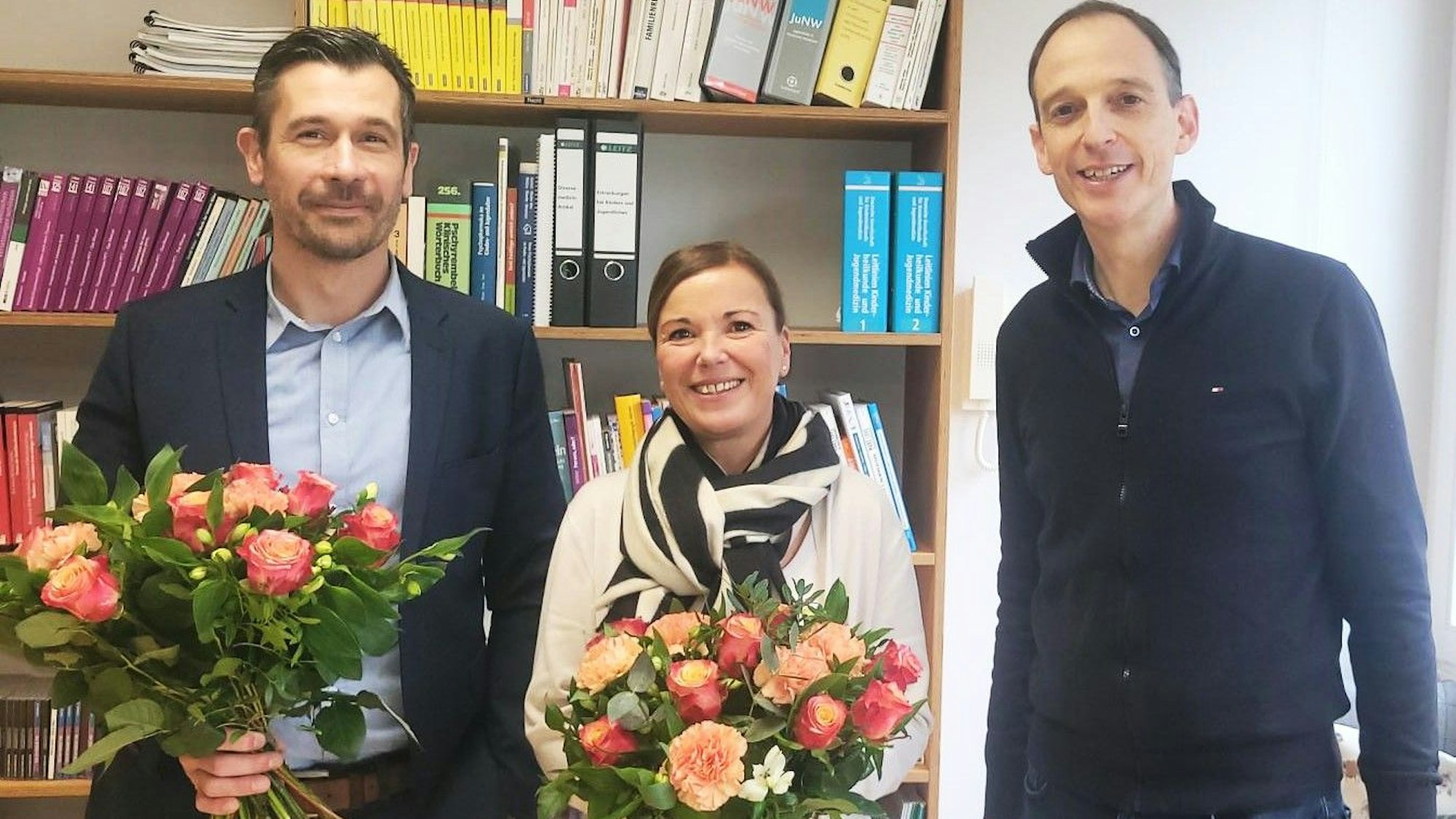 Maik Nohles (l.) und Ulrike Reinartz halten je einen Blumenstrauß. Denis Thelen steht daneben.