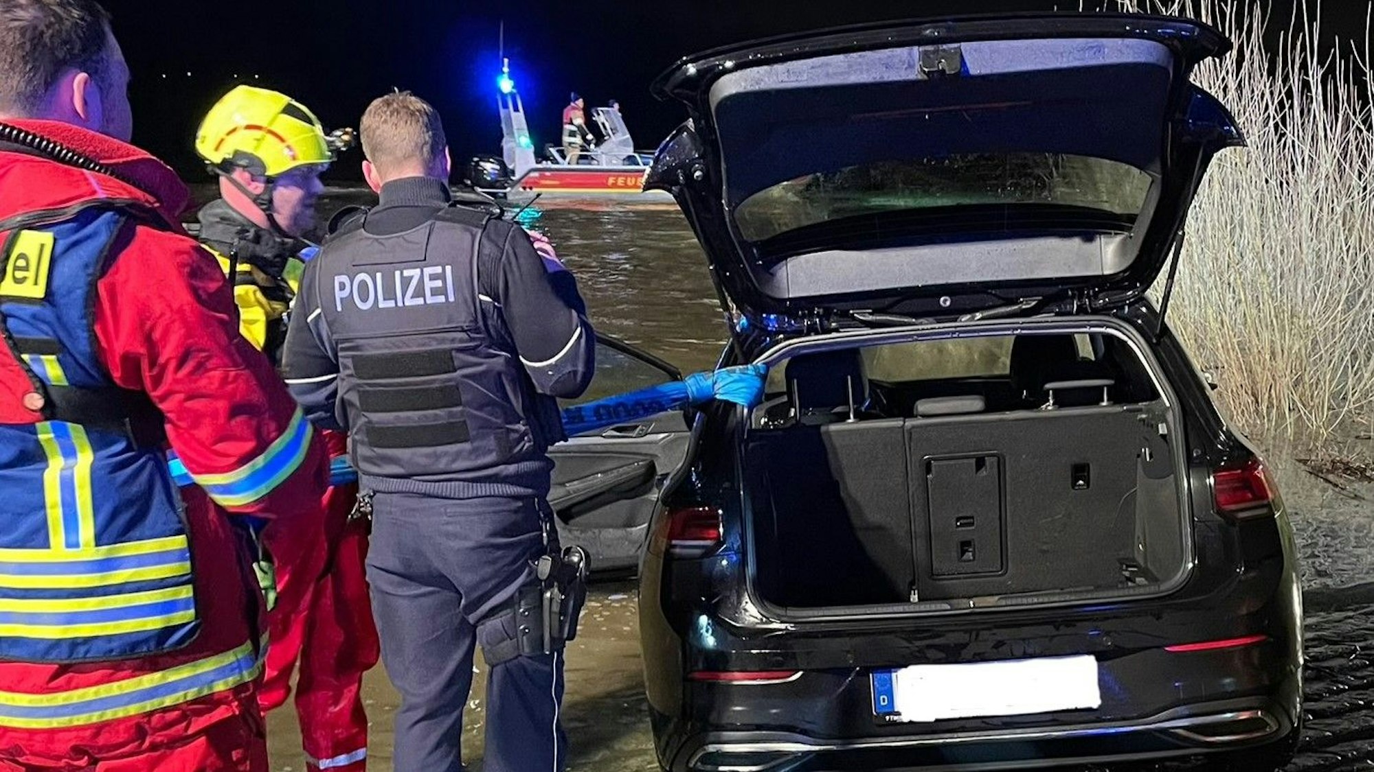 Feuerwehr und Polizei an dem Auto, das aus dem Rhein geholt wurde.