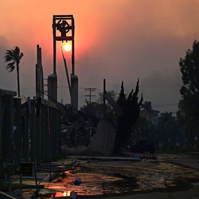The sun is seen through smoke behind the ruins of the Pacific Palisades Presbyterian Church after the passage of the Palisades Fire in Pacific Palisades, California, on January 8, 2025. At least five people have been killed in wildfires rampaging around Los Angeles, officials said on January 8, with firefighters overwhelmed by the speed and ferocity of multiple blazes. (Photo by AGUSTIN PAULLIER / AFP)