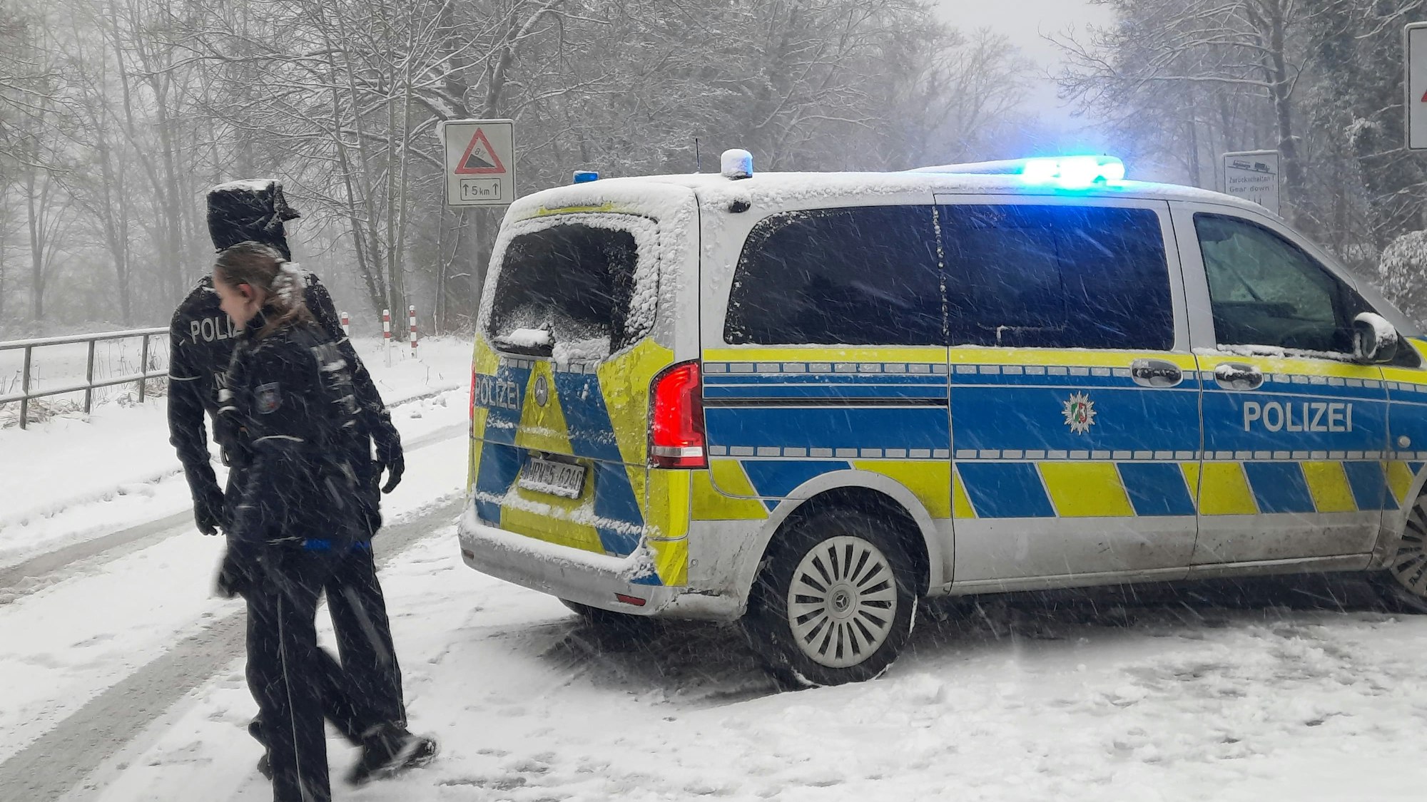 Polizisten auf einer verschneiten Straße.