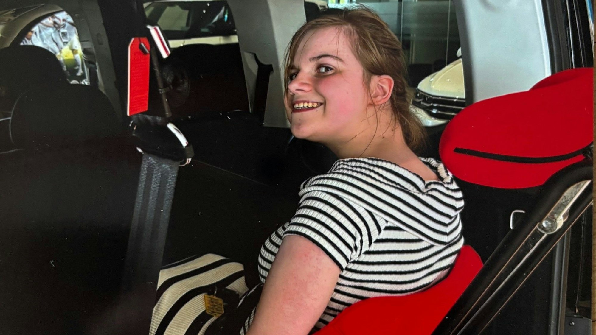 Auf dem Bild ist ein Mädchen zu sehen, das im Rollstuhl in einem Auto sitzt.