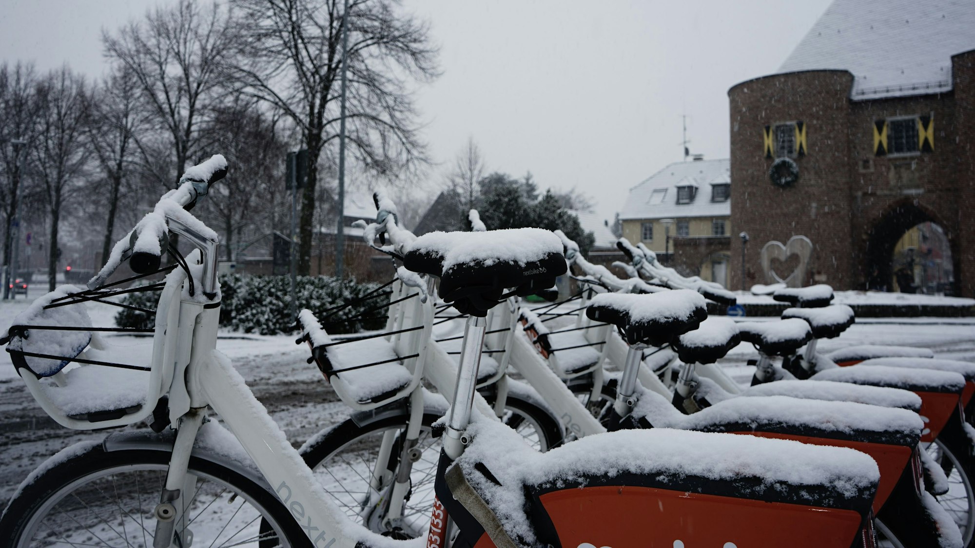 Auf dem Foto sind mit Schnee bedeckte Fahrräder in Bergheim zu sehen.