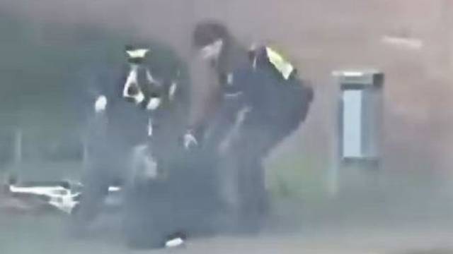 Das Bild zeigt eine Szene aus einem Video und zeigt zwei Polizisten, die auf einen Mann einprügeln.