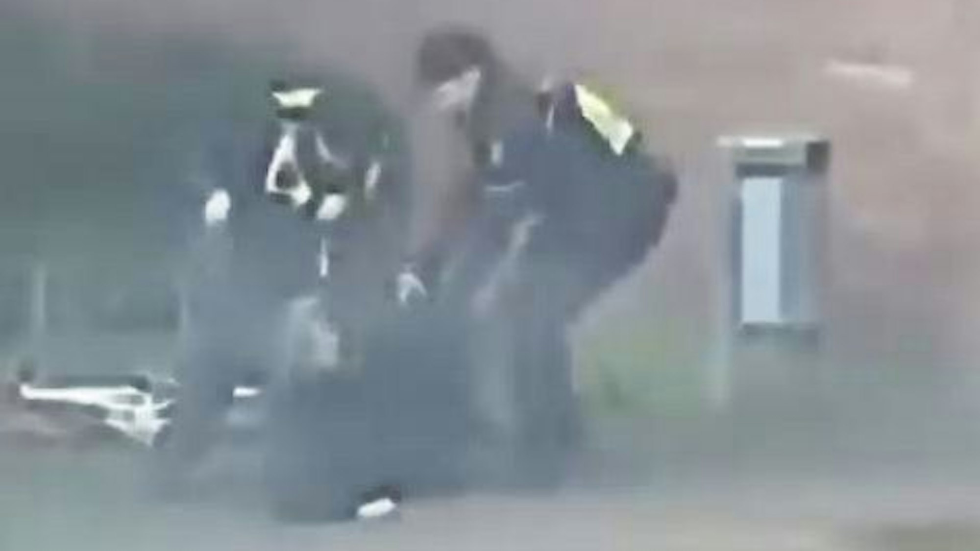Das Bild ist ein Screenshot auf einem Video und zeigt einen Mann am Boden sowie zwei Polizeibeamte.