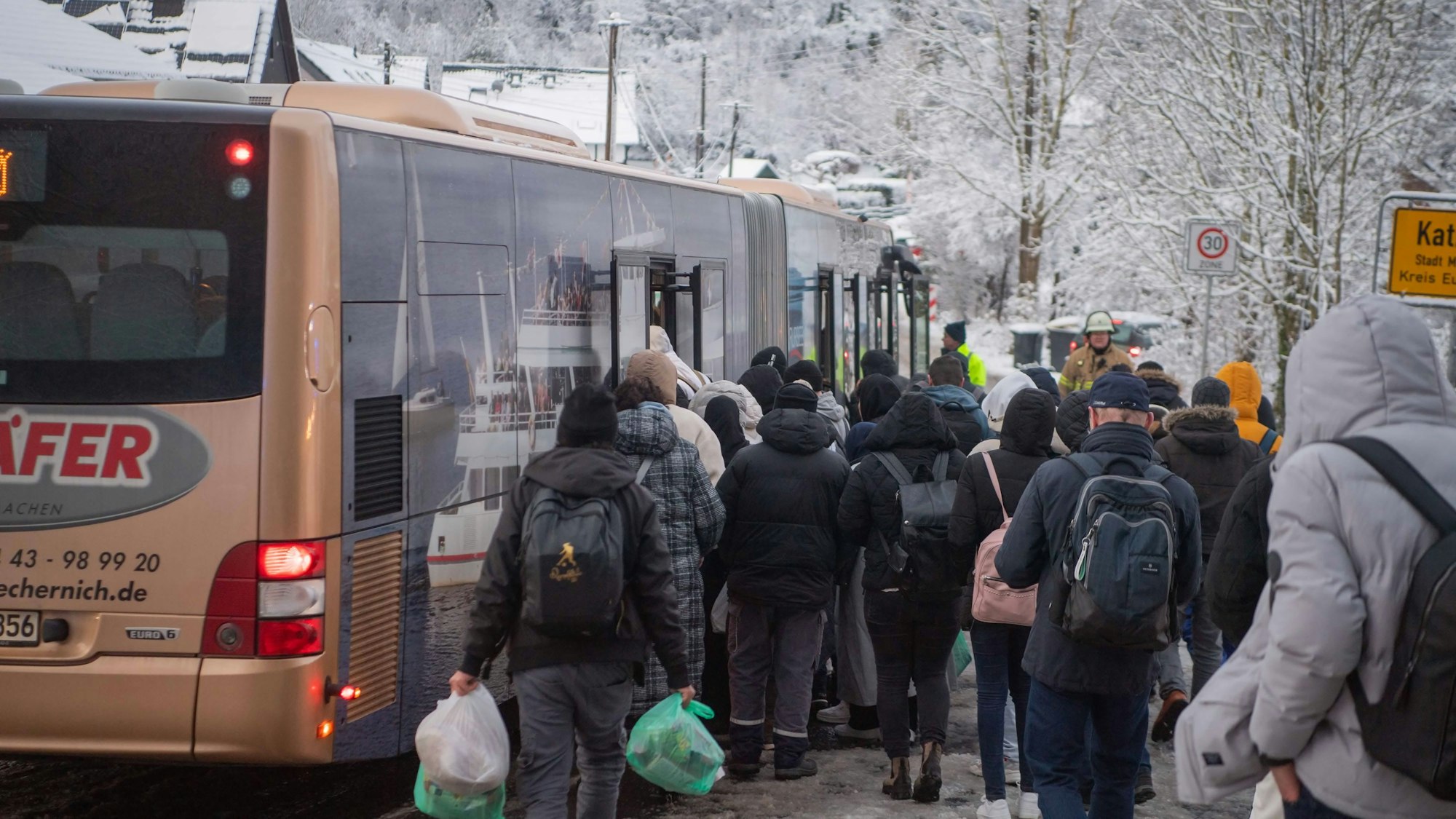 Das Bild zeigt zahlreiche Menschen, die darauf warten, in einen Bus steigen zu können.