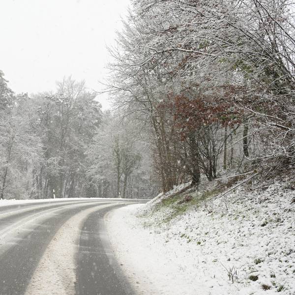 Eine verschneite Straße führt einen Berg hinauf.