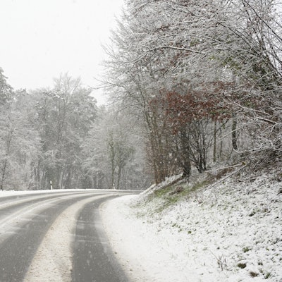 Eine verschneite Straße führt einen Berg hinauf.