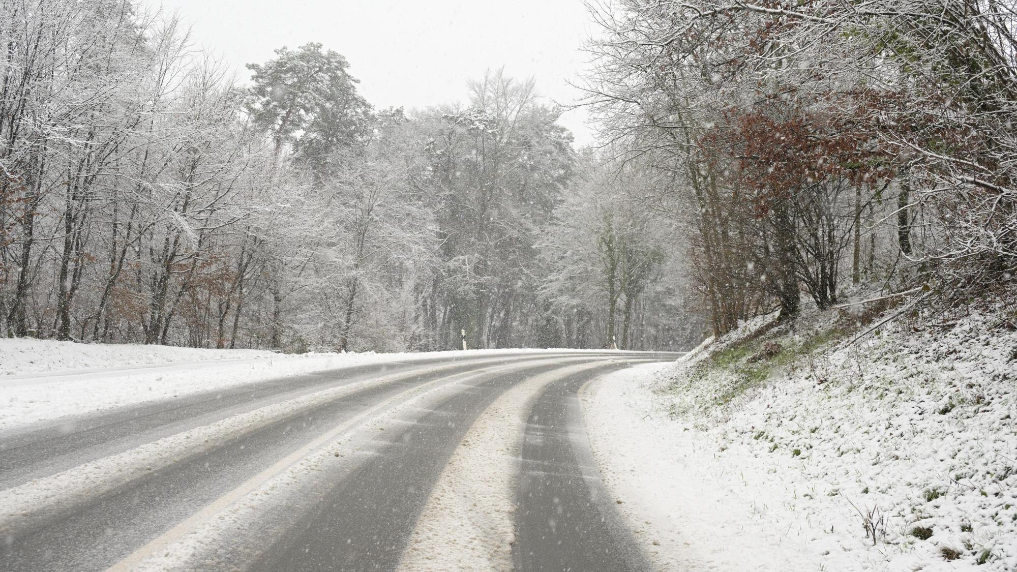 Eine verschneite Straße führt einen Berg hinauf.