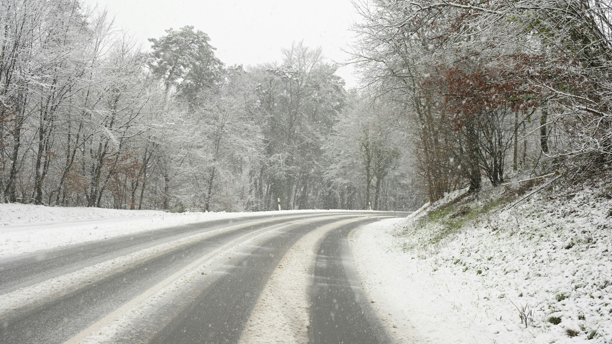 Eine verschneite Straße führt einen Berg hinauf.