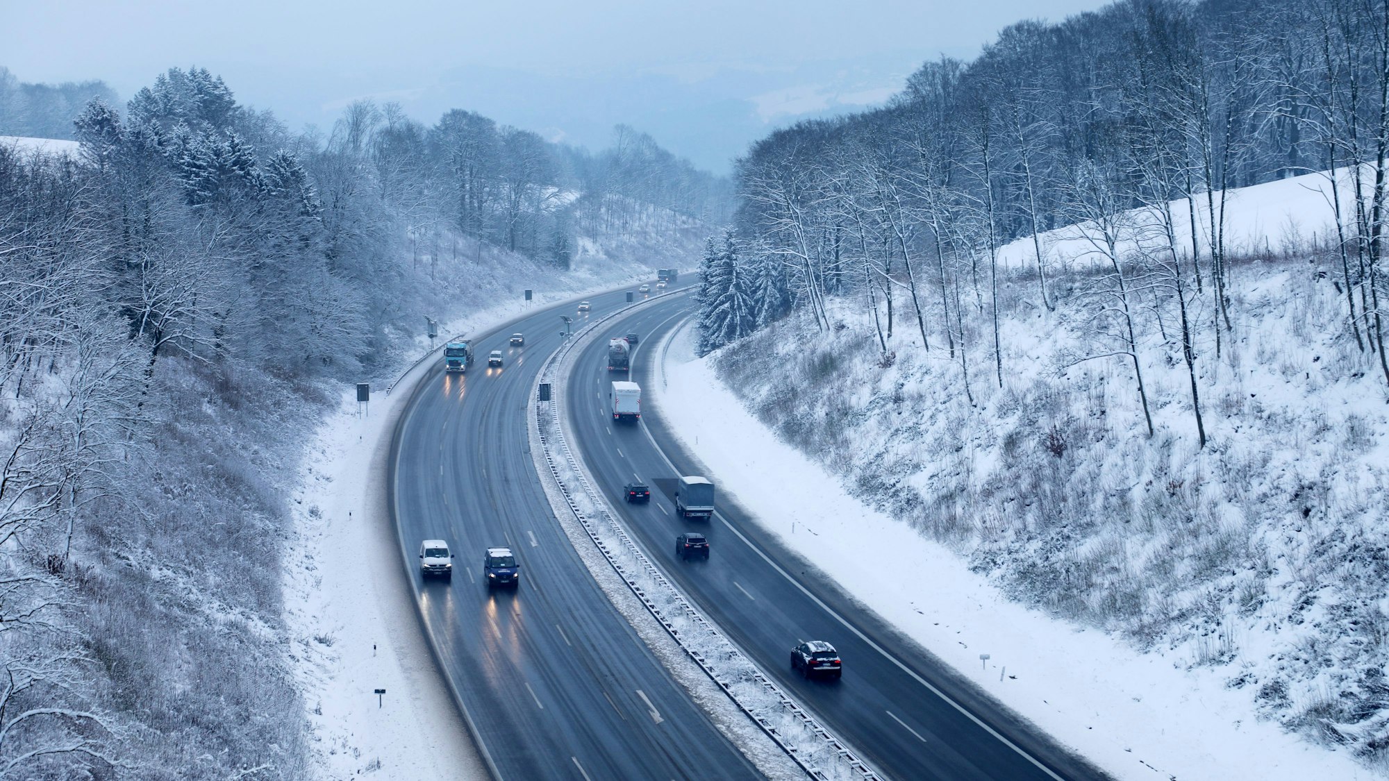 Autos fahren auf der A4 bei Overath durch eine Winterlandschaft.