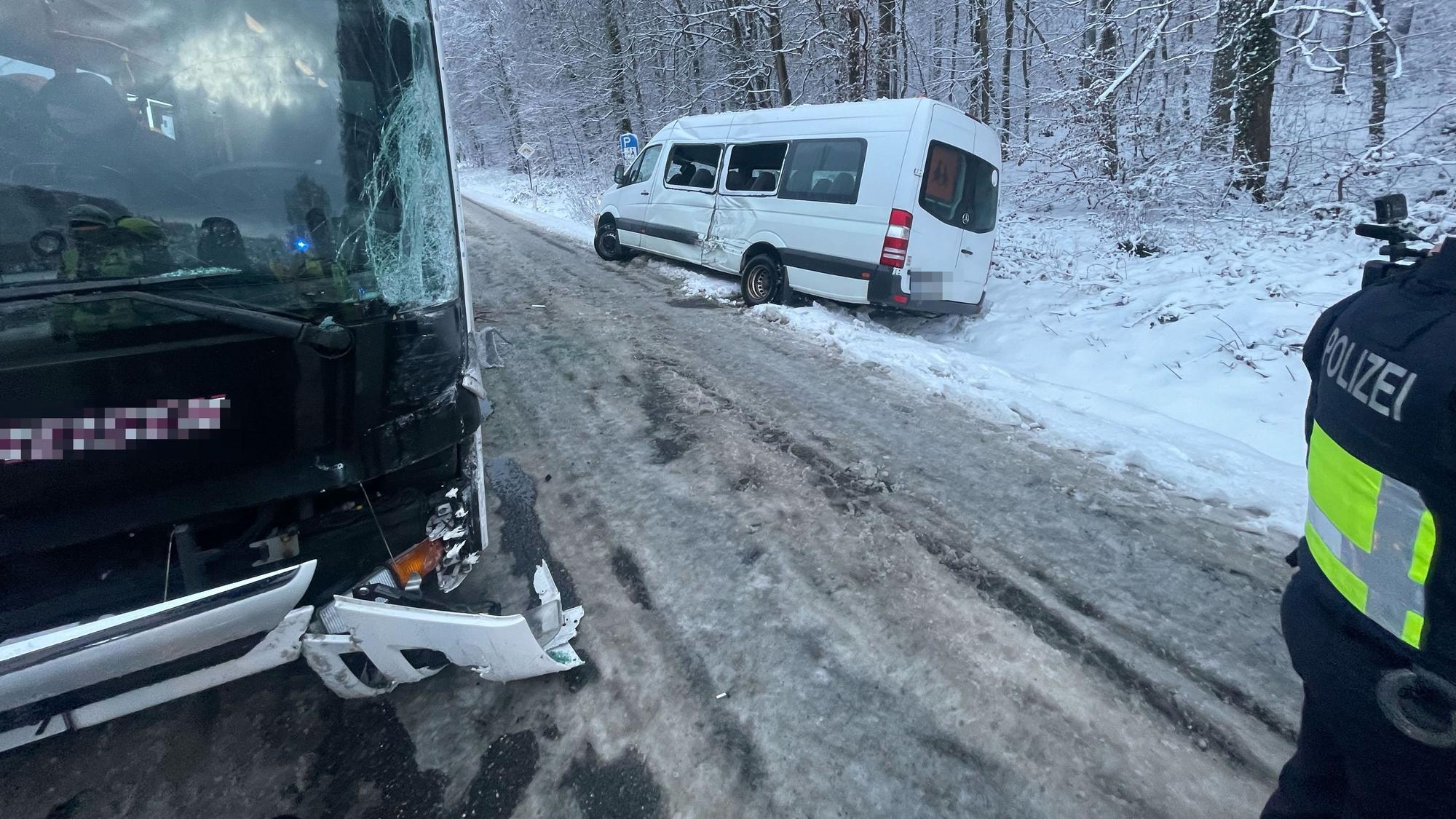 Nach einem Unfall auf einer mit Schnee und Eis bedeckten Straße ist ein beschädigter Kleinbus im Graben, ein Reisebus steht auf der Straße.