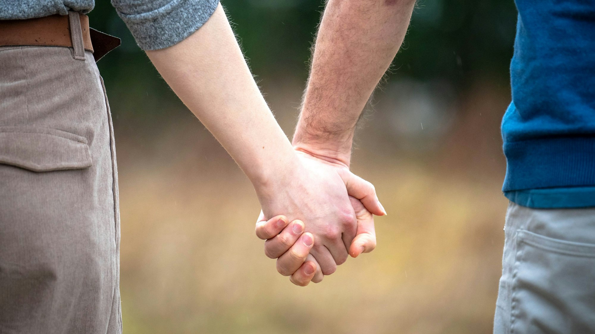 Zwei Menschen halten sich an den Händen.