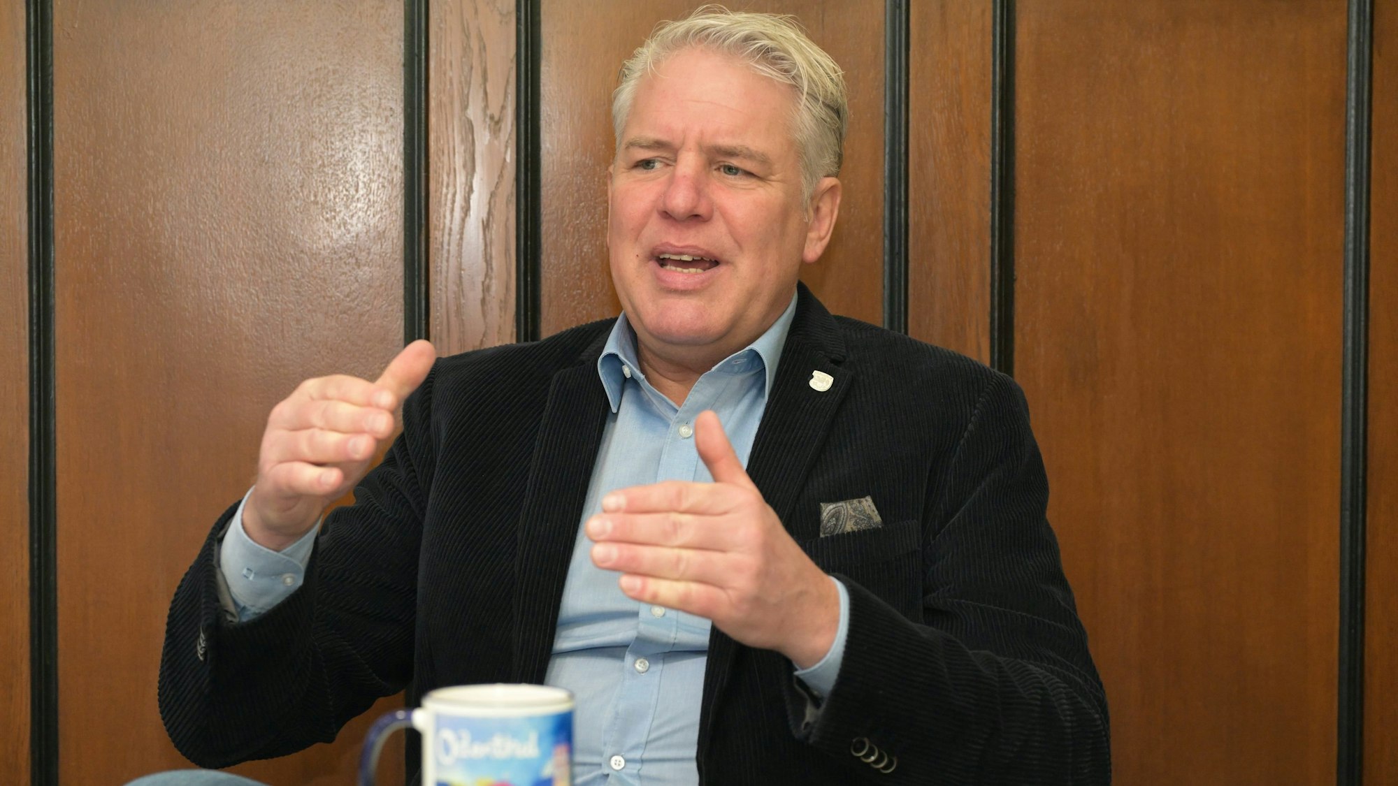 Bürgermeister Robert Lennerts sitzt in seinem Amtszimmer am Tisch und spricht gestikulierend.