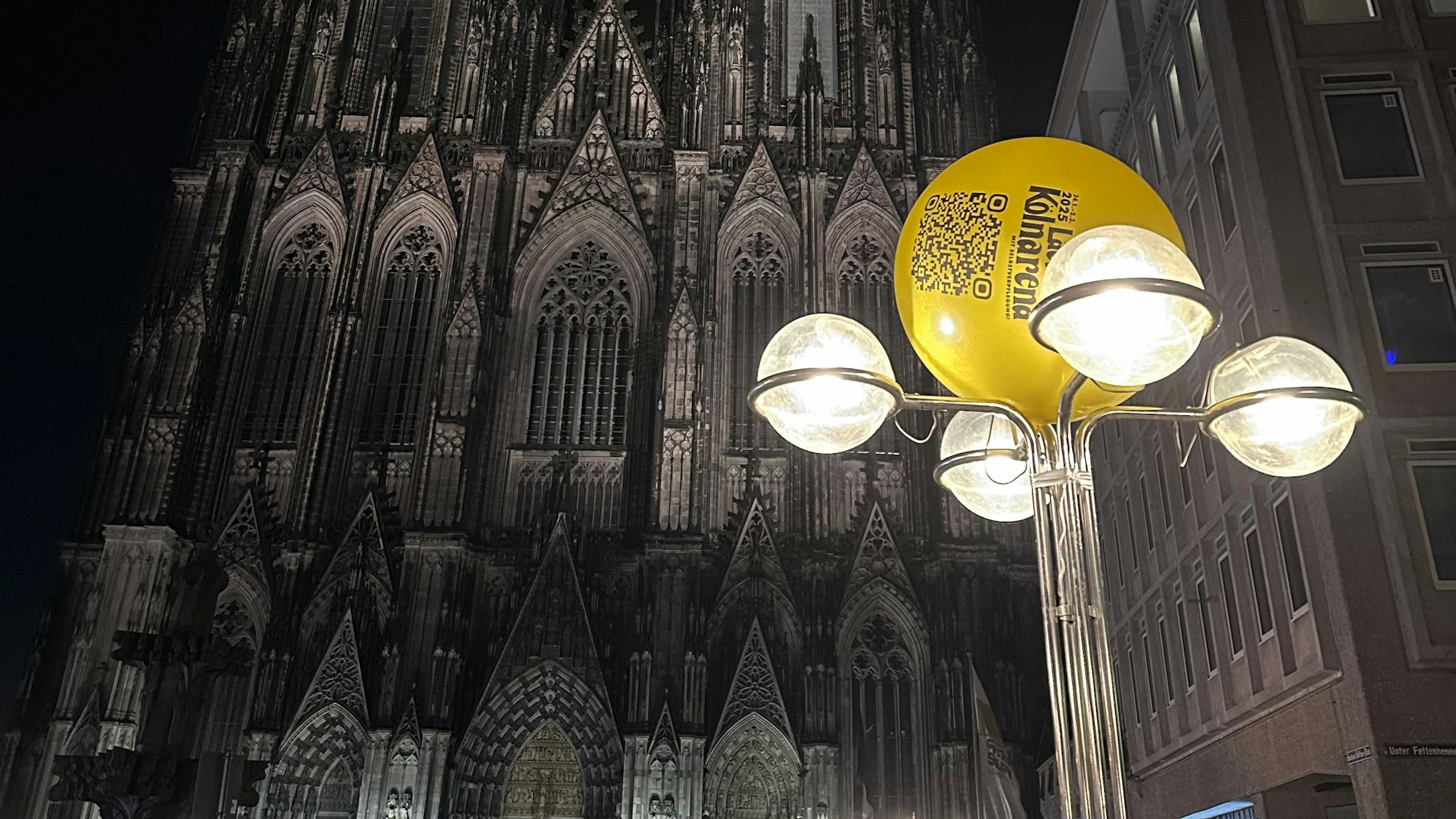 Ein gelber Ballon hängt an einer Laterne am Kölner Dom.