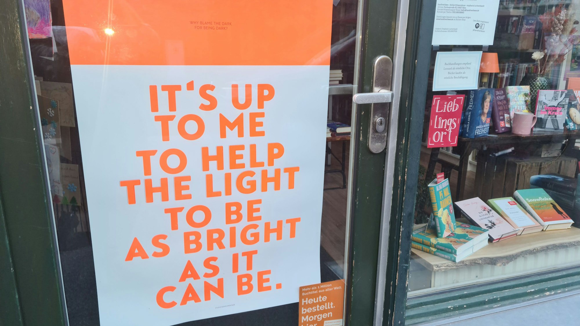 Ein Plakat hängt von innen an der Eingangstür eines Buchladens.