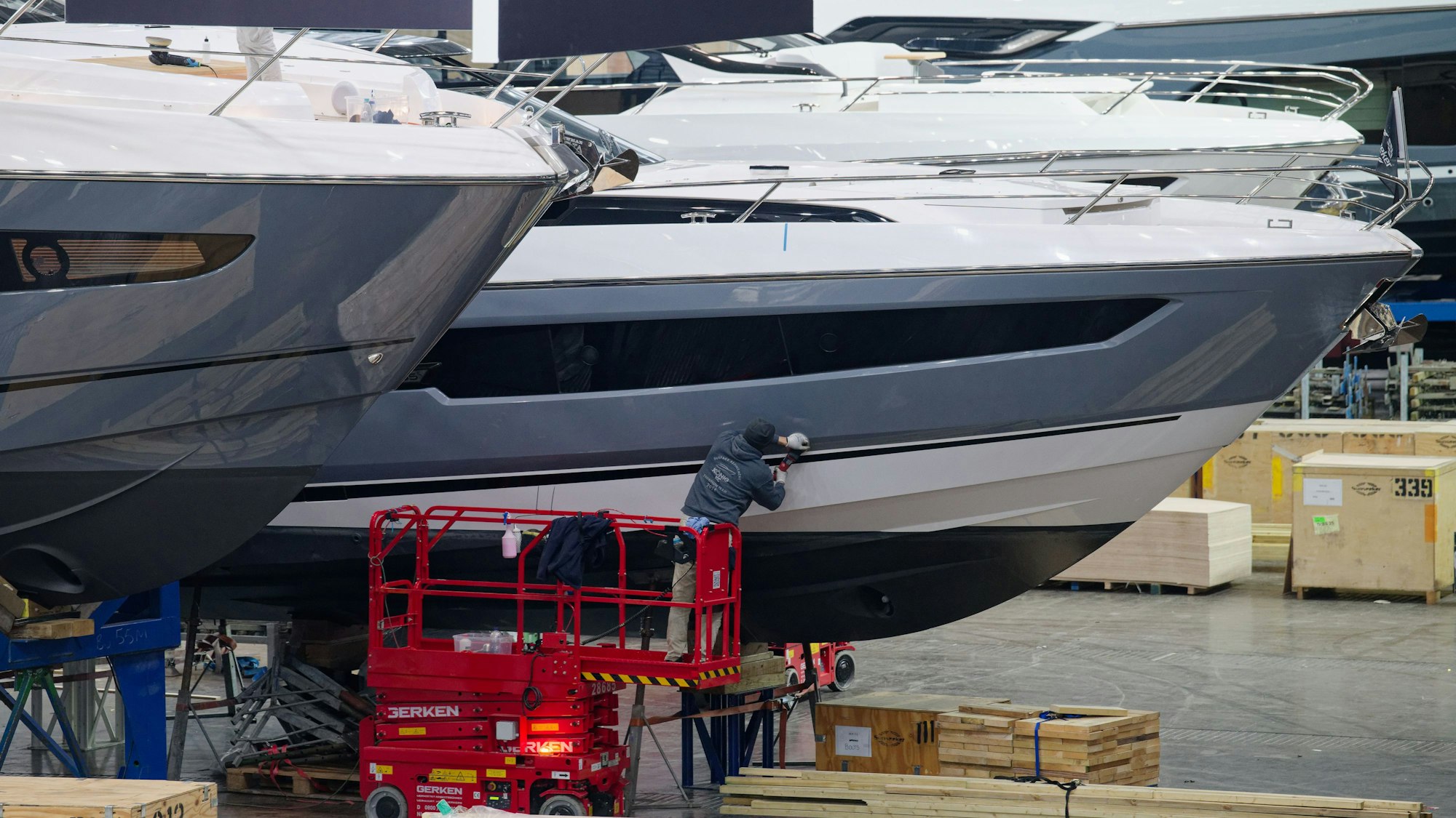 Ein Arbeiter poliert die Außenhülle einer großen Yacht. Die Vorbereitungen für die Wassersportmesse Boot (18 - 26.01.2025) laufen auf Hochtouren.