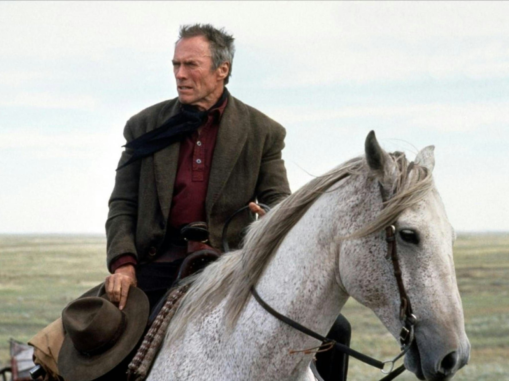 Clint Estwood reitet ein weißes Pferd.