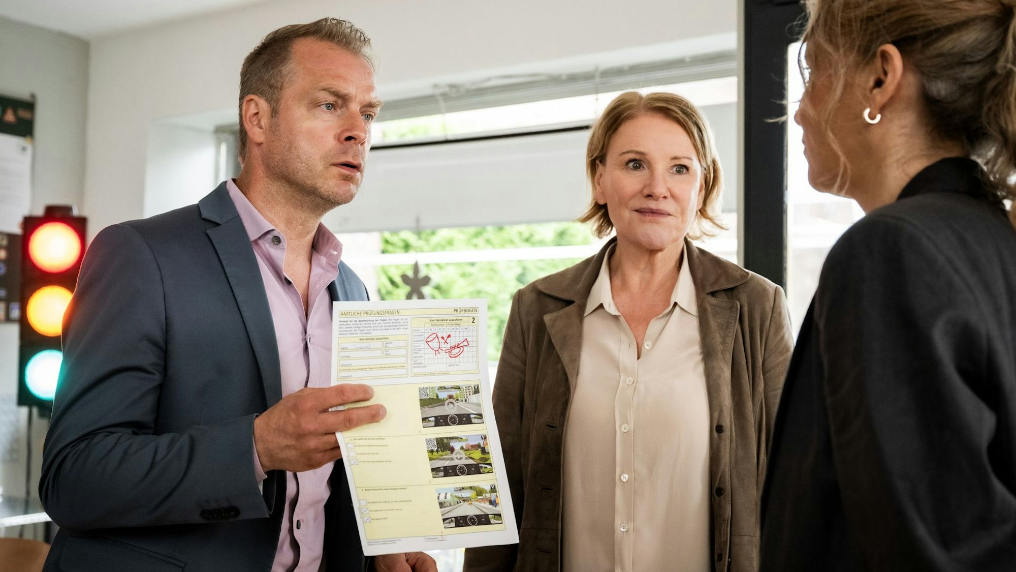 Jürgen Simmel (Hinnerk Schönemann, l.) ist entsetzt, dass er den theoretischen Test in der Fahrschule nicht bestanden hat und stellt Fahrlehrerin Sabine Keuber (Alexandra Schalaudek, r.) in ihrer Fahrschule zusammen mit Marie Brand (Mariele Millowitsch, M.) zur Rede.