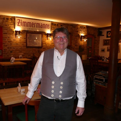 Ein Mann zapft Kölsch aus einem Fass.