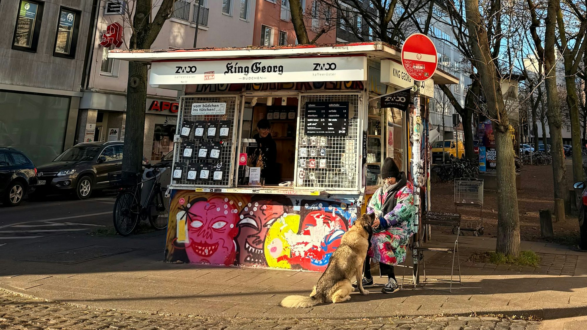 Eine Frau und ihr Hund sitzen vor dem King Georg Büdchen.