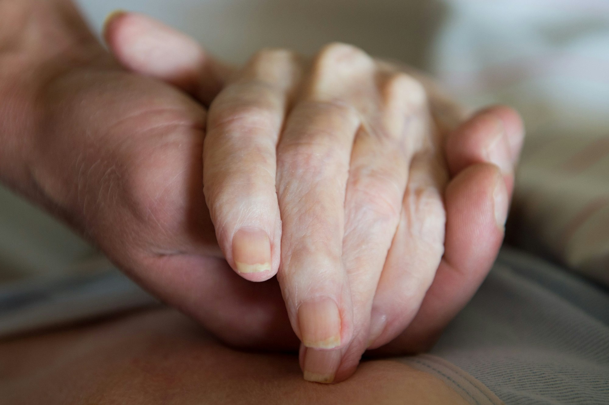 ARCHIV - Ein Pfleger hält die Hand einer pflegebedürftigen Frau.